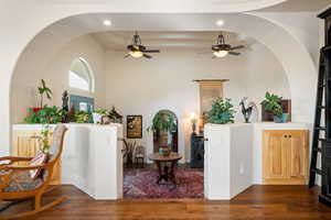 Entryway with dark wood-style floors, arched walkways, a high ceiling, and a ceiling fan