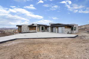 Contemporary home with stone siding, concrete driveway, an attached garage, solar panels, and a mountain view