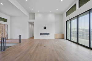 Unfurnished living room featuring light wood-style floors, recessed lighting, and a high ceiling
