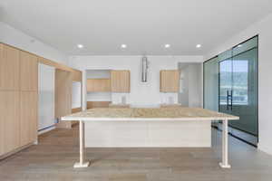 Kitchen with modern cabinets, light wood finish cabinetry, light wood-style flooring, a breakfast bar area, and recessed lighting