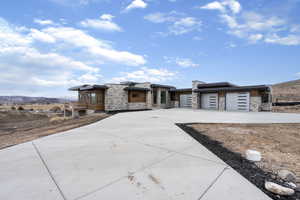 Contemporary house with a mountain view, stone siding, driveway, and a garage