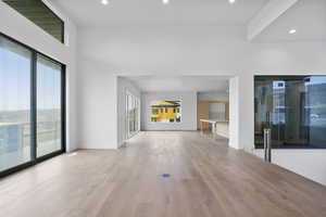 Unfurnished living room with light wood finished floors, recessed lighting, and a high ceiling