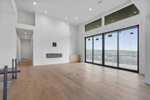 Unfurnished living room featuring recessed lighting, a high ceiling, and light wood-type flooring