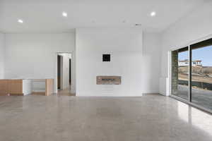 Unfurnished living room featuring recessed lighting and concrete floors