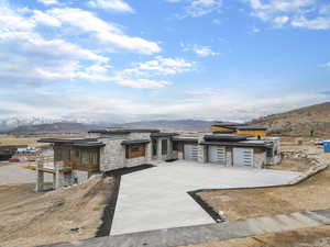 View of front facade featuring a mountain view, stone siding, concrete driveway, and a garage