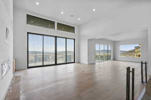 Unfurnished living room with recessed lighting, a high ceiling, light wood-type flooring, and a mountain view