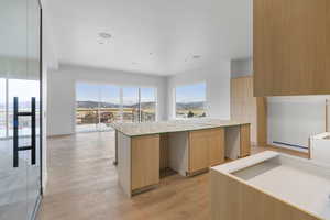 Kitchen featuring light wood finish cabinets, light wood-type flooring, a center island, modern cabinets, and recessed lighting