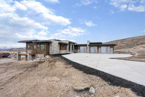 View of front of property featuring stone siding, driveway, a mountain view, and a garage