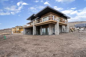 Rear view of property with stone siding, a patio area, and a wooden deck