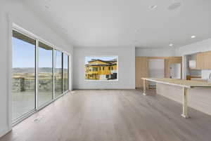 Unfurnished living room featuring light wood-style flooring, a mountain view, and recessed lighting