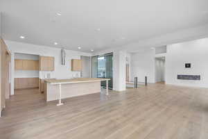Kitchen with a breakfast bar, modern cabinets, open floor plan, a kitchen island, and light wood-style floors
