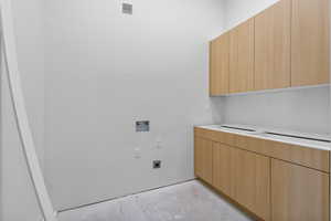 Laundry room featuring unfinished concrete floors, washer hookup, cabinet space, and hookup for an electric dryer