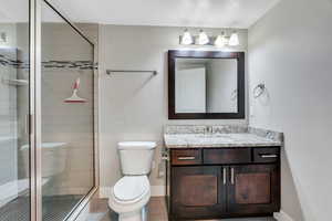 Full bathroom featuring a shower stall, vanity, a textured ceiling, and light wood finished floors