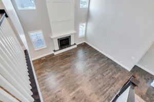 Unfurnished living room featuring a high ceiling, dark wood-style flooring, and a fireplace