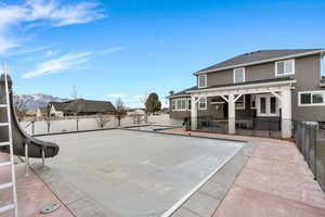 View of pool with a fenced backyard, a water slide, patio surround, and a mountain view