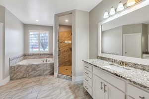 Bathroom with vanity, a garden tub, a shower stall, and light marble finish floors