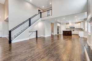 Unfurnished living room with dark wood finished floors, recessed lighting, and a high ceiling