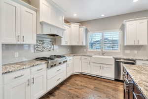Dual tone kitchen featuring light stone counters, stainless steel appliances, dark wood-type flooring, recessed lighting, and tasteful backsplash