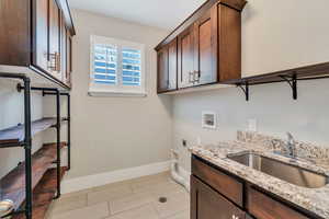 Laundry area featuring hookup for an electric dryer, cabinet space, washer hookup, and wood finish floors