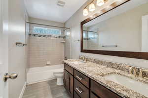 Full bath featuring double vanity and bathing tub / shower combination