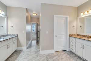 Bathroom featuring two vanities and light marble finish floors