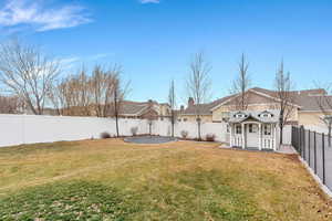 Fenced backyard featuring an outdoor structure and a trampoline