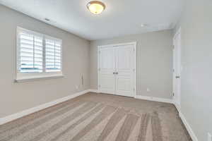 Unfurnished bedroom with light colored carpet and a closet