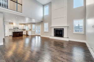 Unfurnished living room featuring dark wood-style flooring, a high ceiling, and a tile fireplace