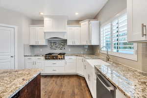 Kitchen featuring dark wood-type flooring, white cabinets, light stone counters, and recessed lighting
