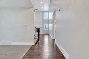 Hallway with dark wood-style flooring, a high ceiling, and recessed lighting