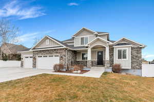 Craftsman-style house featuring board and batten siding, a porch, stone siding, and concrete driveway
