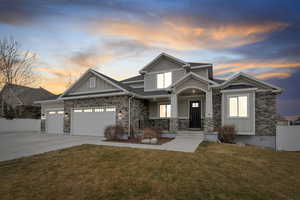 Craftsman inspired home featuring stone siding, board and batten siding, covered porch, and driveway