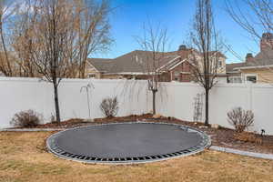 Fenced backyard featuring a trampoline