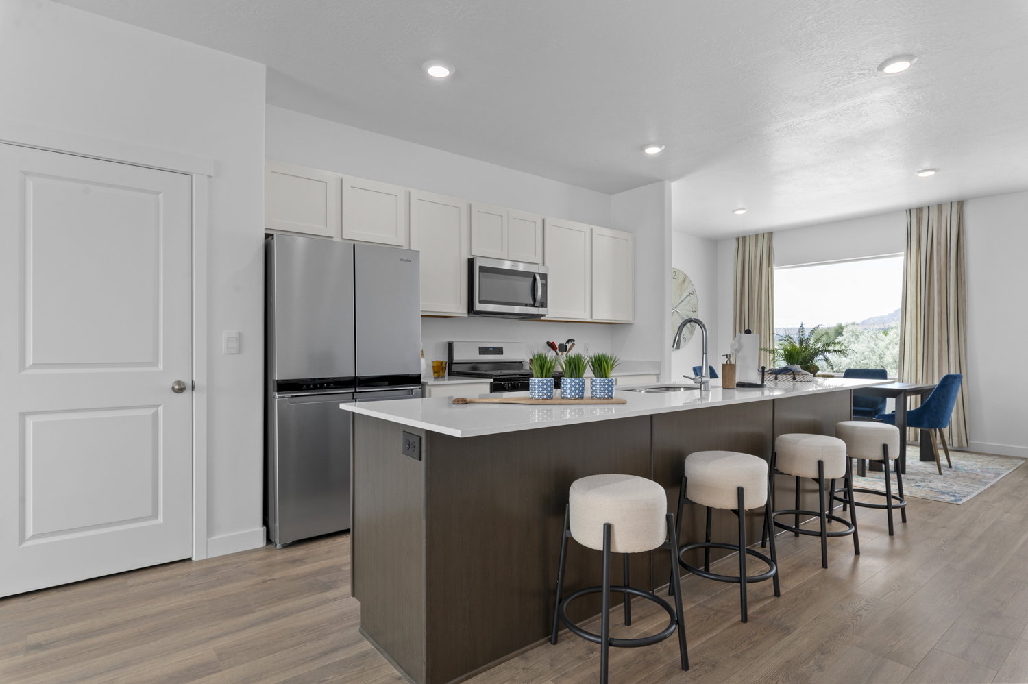 Kitchen featuring stainless steel appliances, an island with sink, a breakfast bar, light wood-style floors, and two tone cabinetry