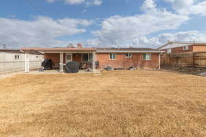Back of property with a fenced backyard, a patio area, brick siding, and a chimney