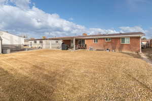 Rear view of house with brick siding, a patio, and a chimney