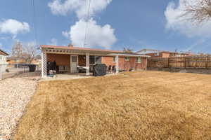 Rear view of house featuring a fenced backyard, brick siding, a patio area, and a chimney