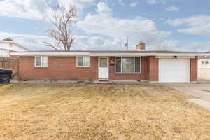 Ranch-style home featuring brick siding, a garage, concrete driveway, and a chimney