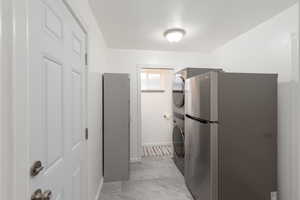 Kitchen featuring freestanding refrigerator and stacked washer / drying machine