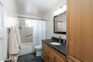Full bathroom featuring vanity, shower / bath combo, and dark tile patterned flooring