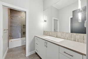 Full bathroom featuring vanity, combined bath / shower with glass door, and tasteful backsplash