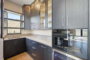 Kitchen featuring glass fronted cabinets, light stone counters, and beverage cooler