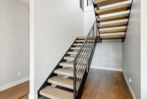 Staircase featuring hardwood / wood-style floors and baseboards