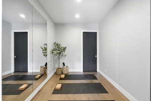 Exercise room with wood finished floors and recessed lighting