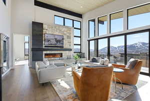 Living area with hardwood / wood-style flooring, a stone fireplace, and a high wood ceiling