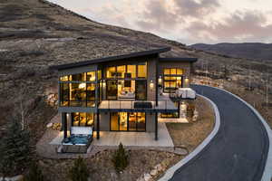 Rear view of house with a patio area, a mountain view, a hot tub, and a balcony