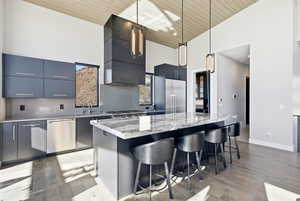 Kitchen featuring modern cabinets, tasteful backsplash, a high wood ceiling, hanging light fixtures, and a breakfast bar