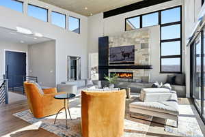 Living room with wood finished floors, a fireplace, a high ceiling, and healthy amount of natural light