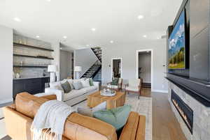 Living area with wood-type flooring, a large fireplace, wet bar, and recessed lighting