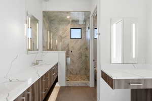 Bathroom with double vanity, a marble finish shower, and light tile patterned floors